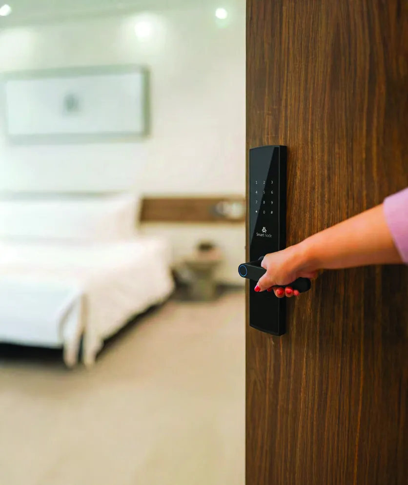 A hand opening a door fitted with a black digital lock with a keypad