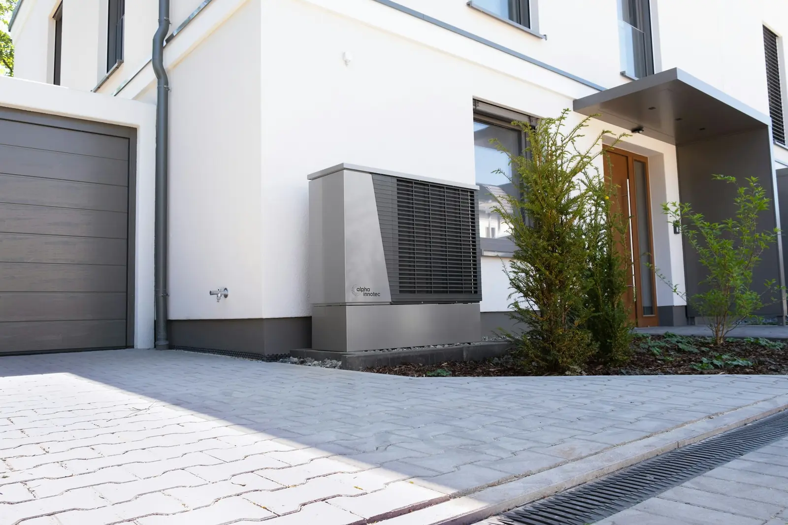 An outdoor heat pump unit beside a modern house entrance
